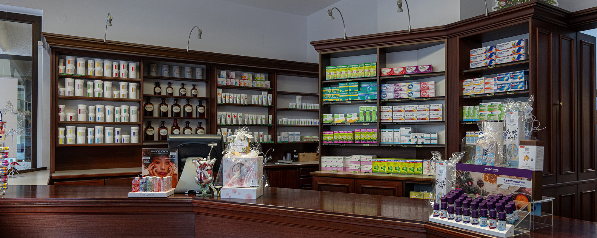 Innenraum einer Apotheke mit Verkaufstresen, Regalen voller Produkte und einem einladenden, gut strukturierten Layout.